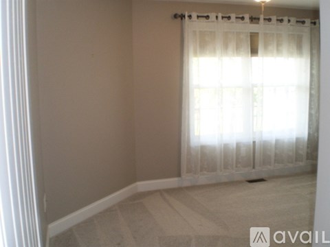 A room with a window covered by a white curtain.