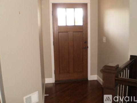 A brown door with a window above it in a room.