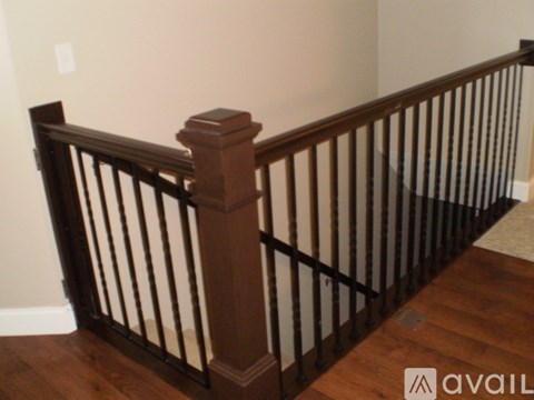 A wooden staircase with a dark railing.