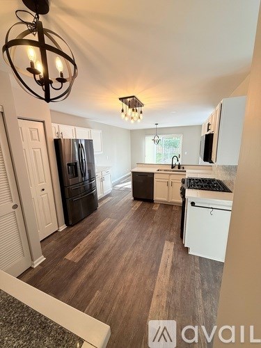 A kitchen with white cabinets and a black fridge.