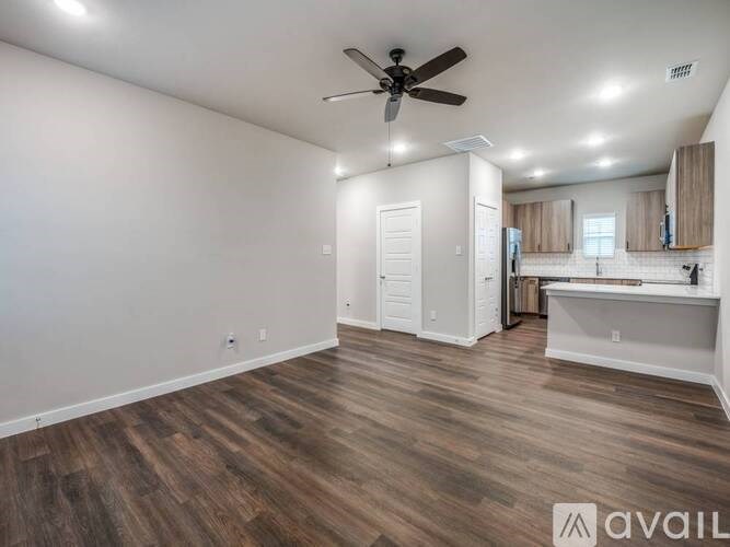 A spacious room with wood flooring and a ceiling fan.