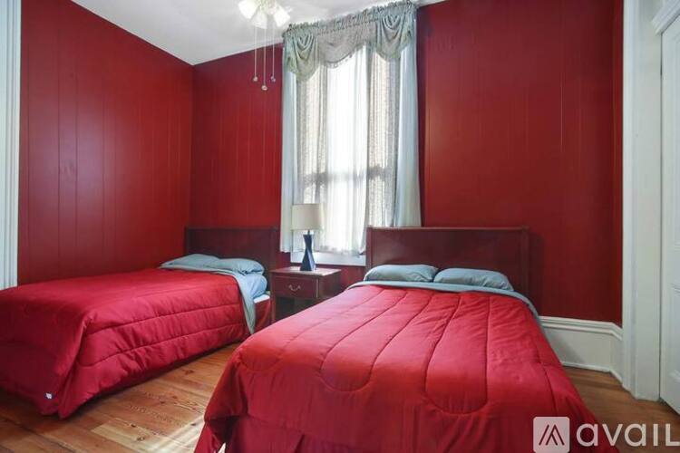 Two red beds in a room with wooden floors and white walls.
