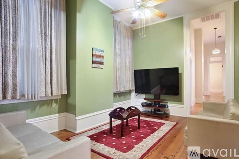 A living room with a television and a red rug.