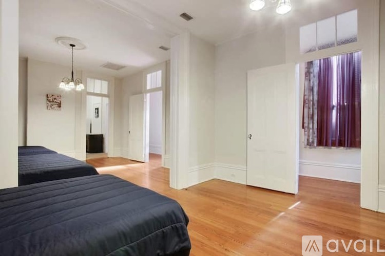 A bedroom with a bed, a chandelier, and a door leading to another room.