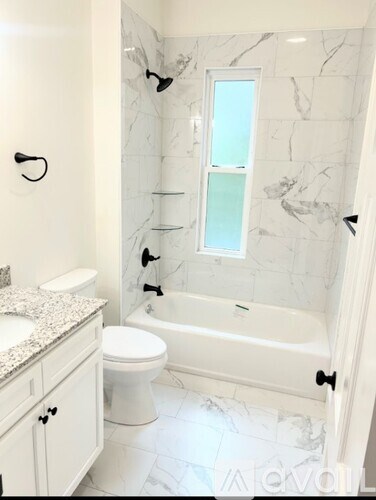 A white bathroom with a marble wall and a white tub.