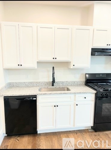 A kitchen with white cabinets and black appliances.