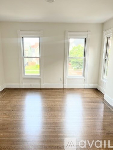 A room with wooden floors and two windows.