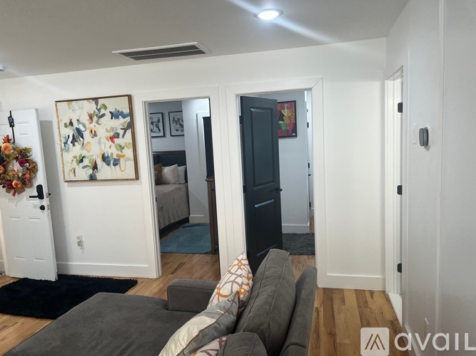 A living room with a grey couch and a painting on the wall.