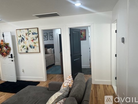 A living room with a grey couch and a painting on the wall.