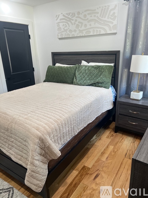 A bedroom with a large bed and a painting on the wall.