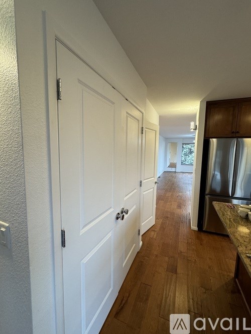 A hallway with white doors and a wooden floor.