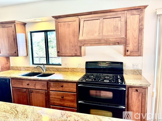A kitchen with a black stove top oven and wooden cabinets.