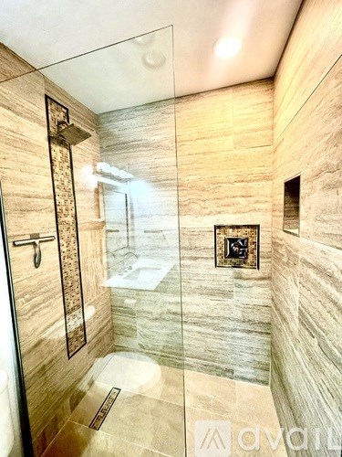 A bathroom with a walk-in shower and a glass door.
