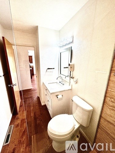 A bathroom with a toilet, sink, and mirror.