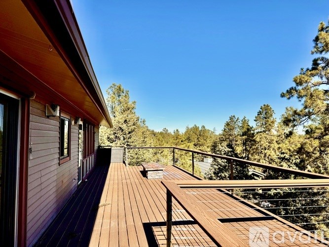 A wooden deck with a railing and a view of trees.