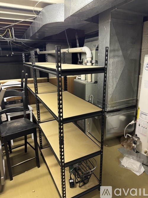 A room with a metal shelf and a black chair.