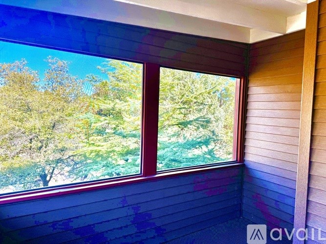 A room with a window showing a view of trees.