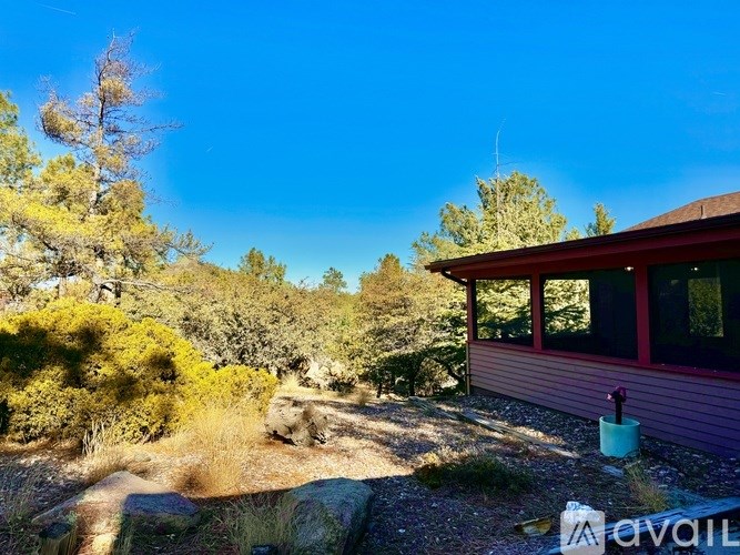 A house with a red roof is surrounded by trees and rocks.