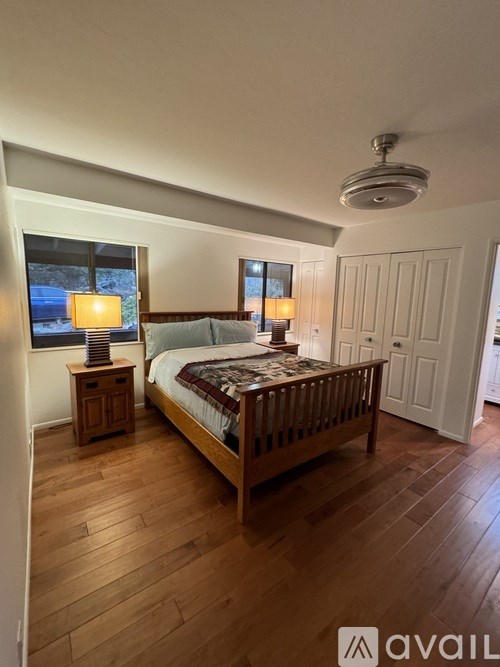 A bedroom with a bed, nightstands, and a window.