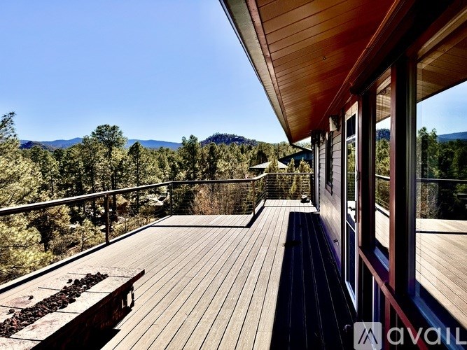 A wooden deck with a bench overlooks a mountainous landscape.