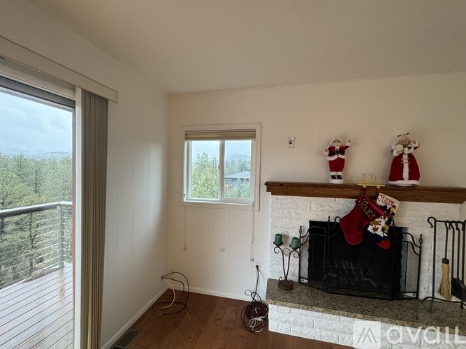 A room with a fireplace and a window overlooking a wooded area.