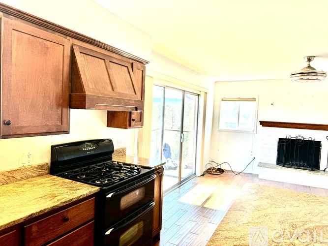 A kitchen with a black stove top oven and wooden cabinets.