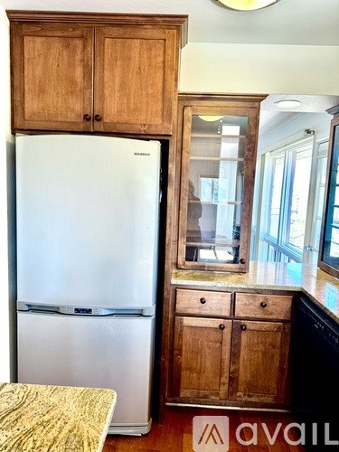 A white fridge in a kitchen with wooden cabinets.
