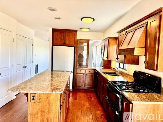 A kitchen with wooden cabinets and a marble countertop.