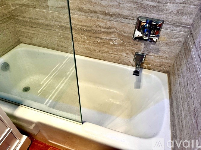A white bathtub with a glass shower door in a bathroom.