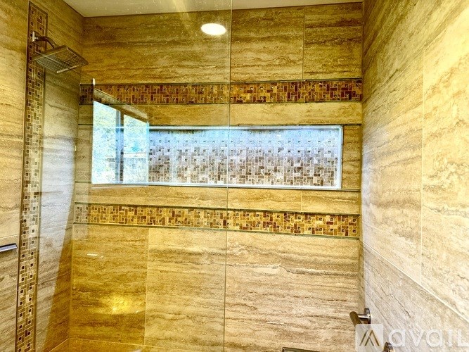 A bathroom with a gold and beige tiled wall and floor.
