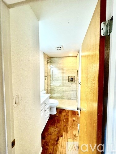 A bathroom with a toilet, sink and wooden floors.