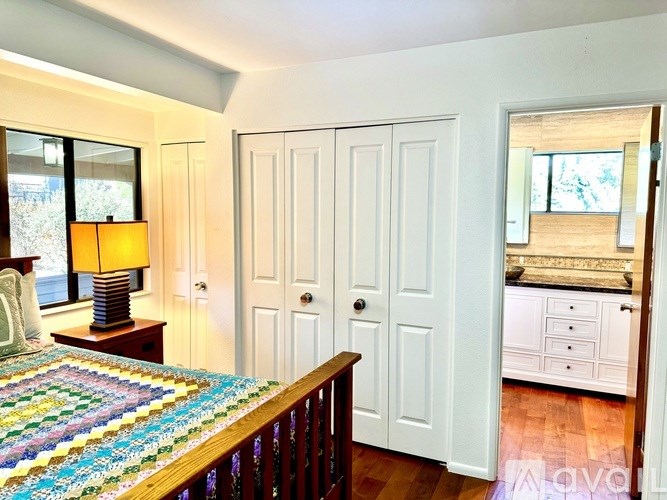 A bedroom with a bed, a lamp, and a dresser.