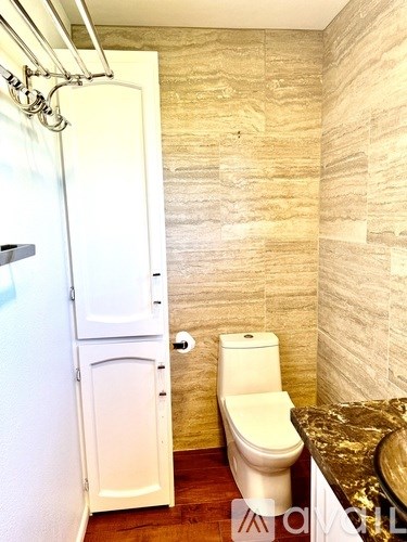 A white toilet sits next to a white shower stall in a bathroom.