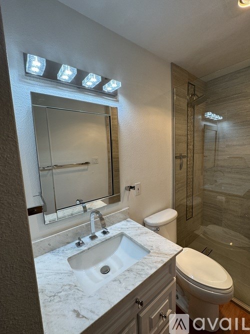 A bathroom with a marble countertop and a walk-in shower.