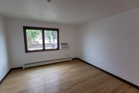 A room with a window and wooden flooring.