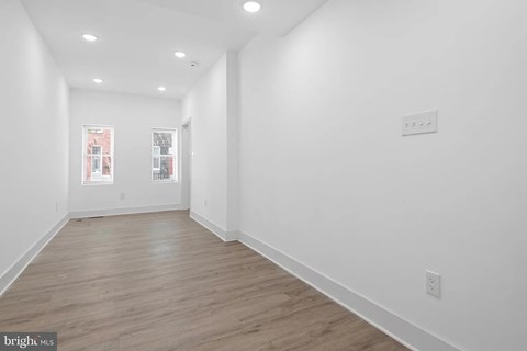 A long, empty hallway with wood floors and white walls.