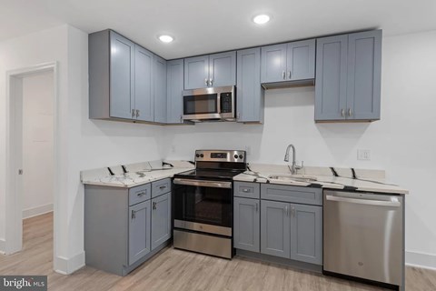 A kitchen with grey cabinets and stainless steel appliances.