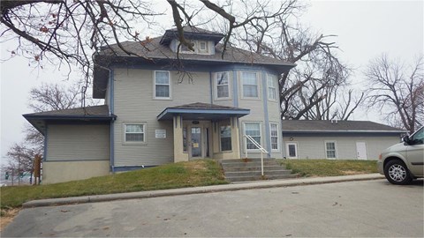 A grey house with a car parked in front.