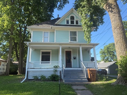 A blue house with white trim and a brown door.