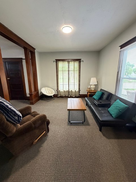 A living room with a brown couch, a wooden table, and a lamp.
