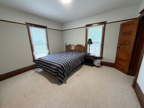 A bedroom with a bed, nightstand, and window.