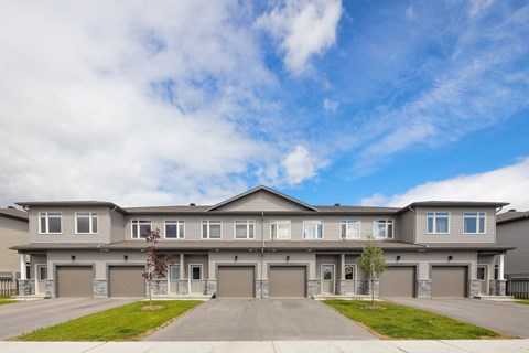 A large grey house with a grey front yard.