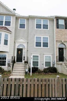 A two story house with a black door and a small porch.
