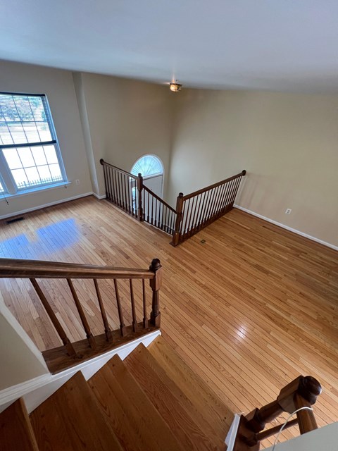 A wooden staircase with a railing leads up to a window.
