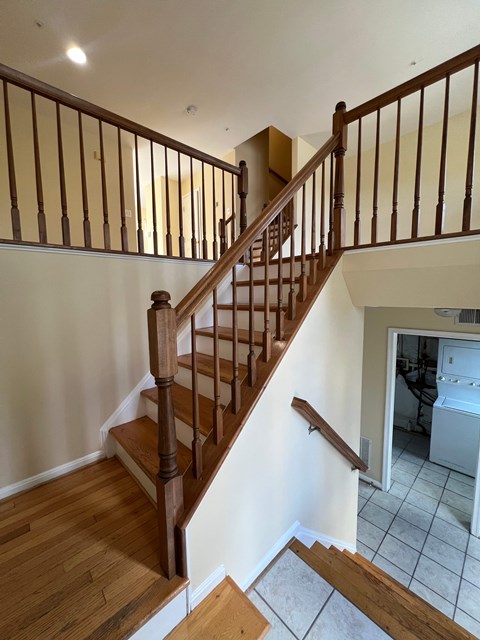 A wooden staircase with a white wall on the side.