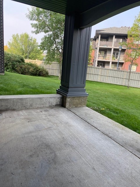 A concrete porch with a grey pillar and a green lawn.
