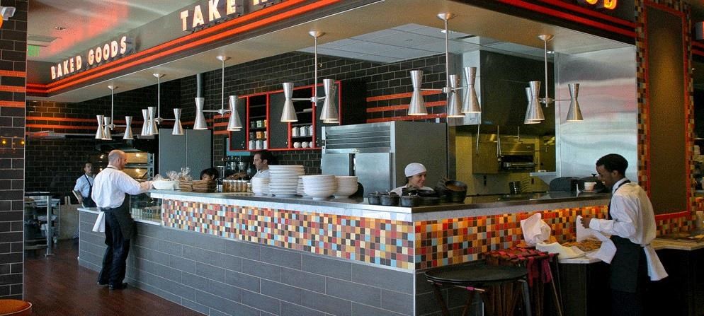 a restaurant with people preparing food at the counter