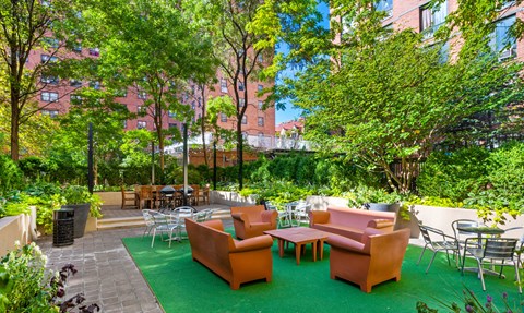 A patio with orange chairs and tables surrounded by trees.
