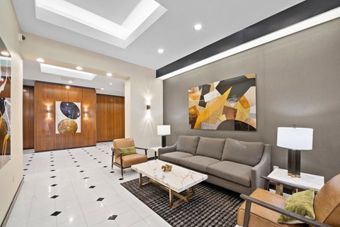 A modern living room with a grey sofa, a coffee table, and a large abstract painting on the wall.