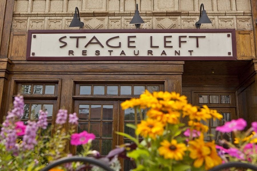 a sign for stage left restaurant on a building with flowers
